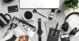 Flat lay of a stylish workspace with laptop, phone, coffee, and tech accessories.